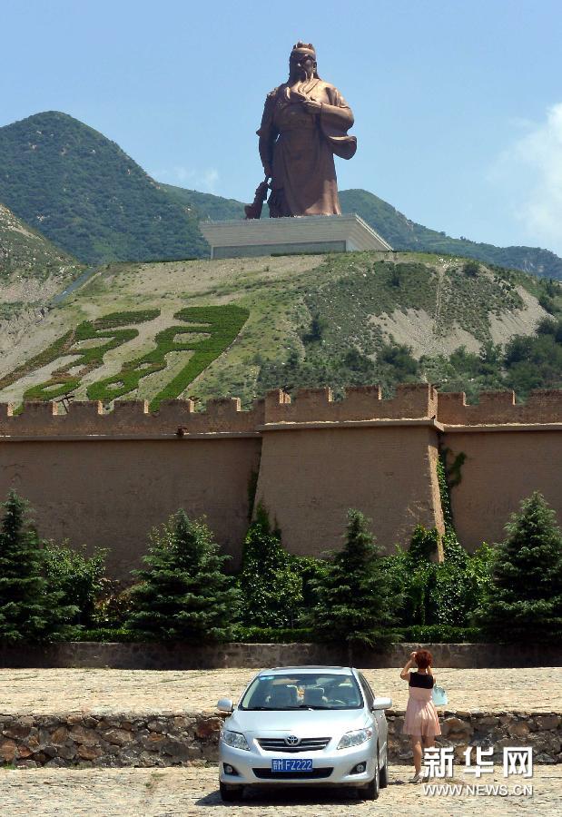 在山西省运城市的关公圣像景区，一位游客在拍摄远处山坡上的关公塑像（7月2日摄）。