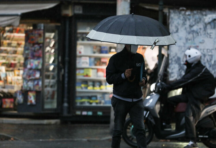 10月14日,在意大利首都罗马,一名男子戴着口罩走在雨中.