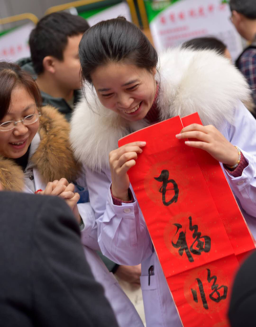 图片默认标题_fororder_作为志愿者来为市民服务的一医院的医护工作者在获得其他志愿者赠送的春联时露出甜美的笑容！
