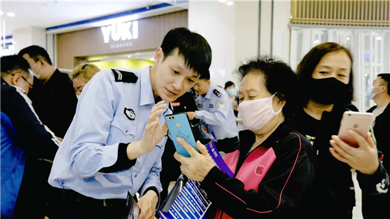 鞍山公安启动“功勋警犬反诈钢城行”活动 市民能和警犬互动_fororder_民警现场指导群众安装App，形成手机终端技术反诈保护屏障 摄影：孙彦辉