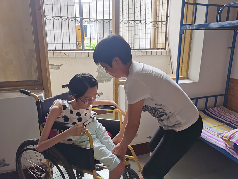 谭伍越:“不普通”的身体拥有超越平凡的力量 高考成绩优异努力奔向未来_fororder_母亲正在照顾谭伍越-摄影-潘建勇