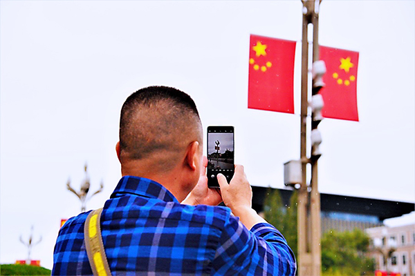 挂国旗迎国庆 “中国红”闪耀成都街头_fororder_市民拿出手机拍照--供图-成都市城管委