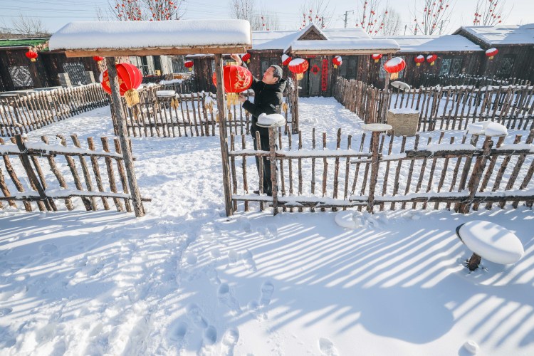 2021年12月30日,工人在河北省遵化市团瓢庄乡山里各庄村的雪乡风情街