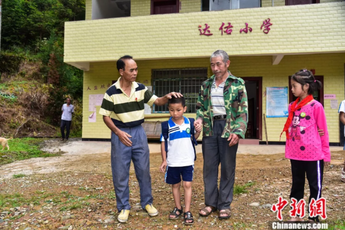 「中新社」杀了自家过年的大猪建教学楼，他用一根扁担撑起一座学