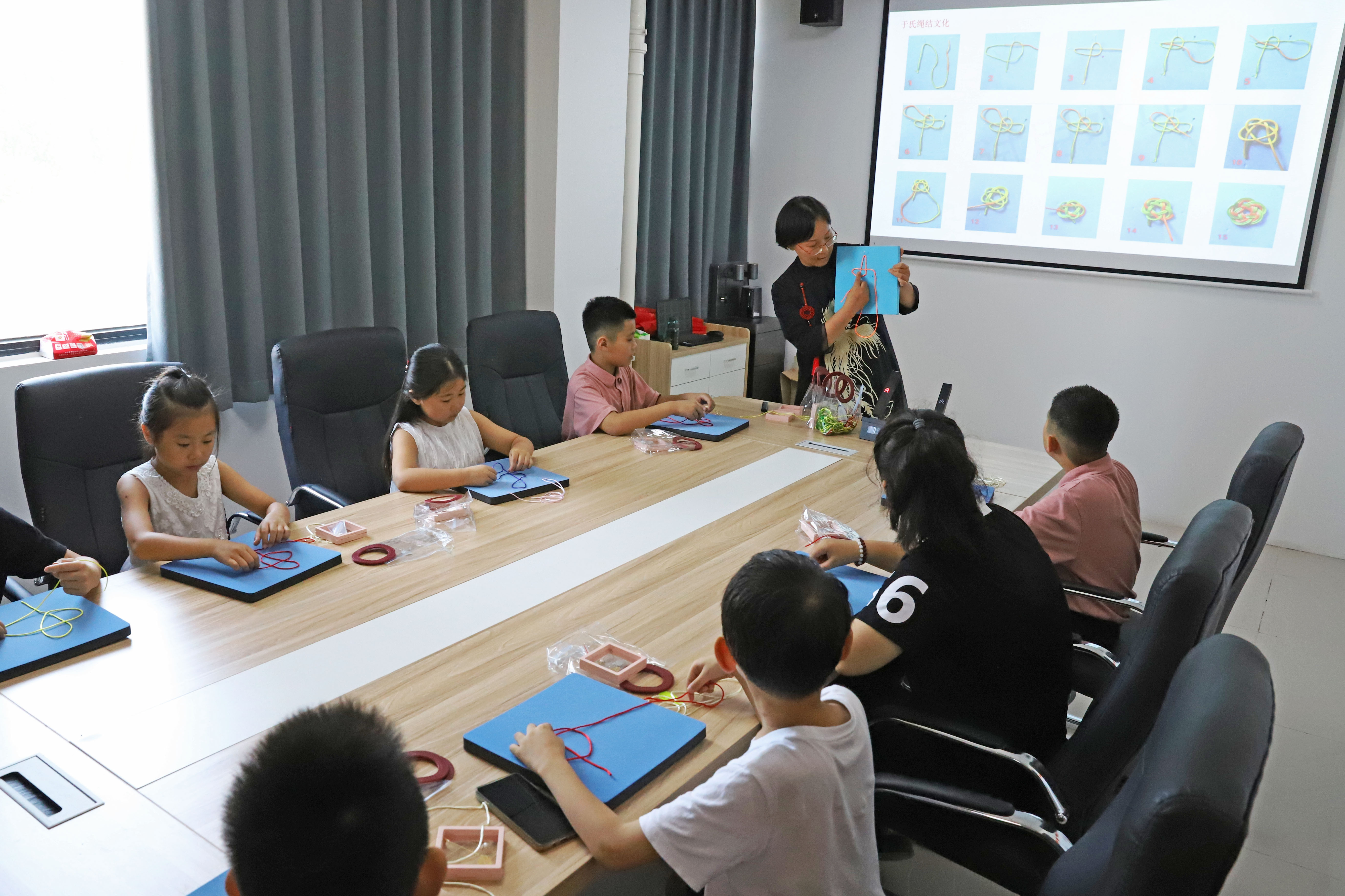河北涿州:学生们假期生活增添“非遗色”_fororder_7月16日,涿州市非遗人传承人于长娟给学生们讲解绳结编织技艺。熊华明摄