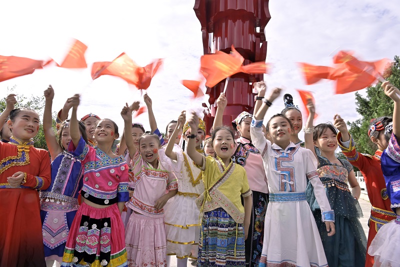 【原创】144.5 万人次 信阳新县“双节”旅游人气旺_fororder_在“红旗飘飘”主题雕塑前，孩子们挥舞着国旗对祖国的热爱和祝福。（焦汉平  摄）