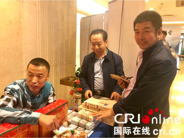 山西白老大食品有限公司董事长白桂智(右)热情地向与会嘉宾介绍广灵县