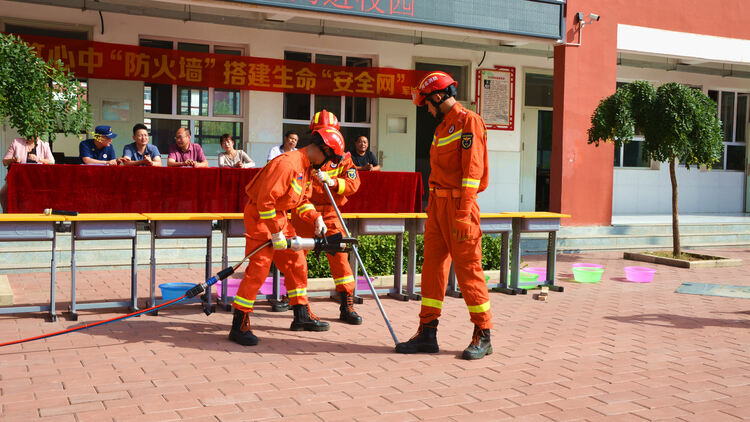 (原创)河北唐县:共筑心中防火墙 搭建生命安全网_fororder_消防员正向学生们演示破拆工具如何使用 (3).JPG