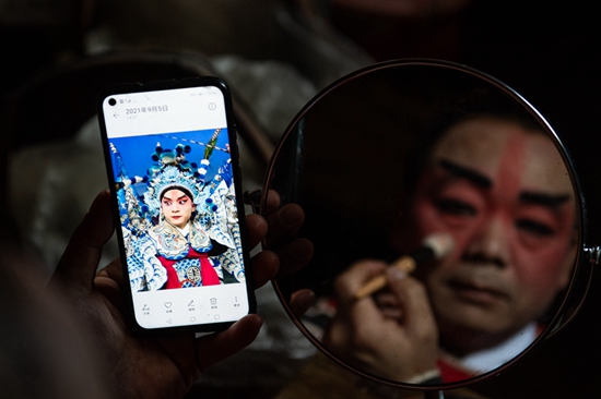 贵州天柱：一“机”在手传戏韵_fororder_1、天柱县石洞镇汉寨侗戏班演员利用手机对照网上收集来的脸谱化妆。