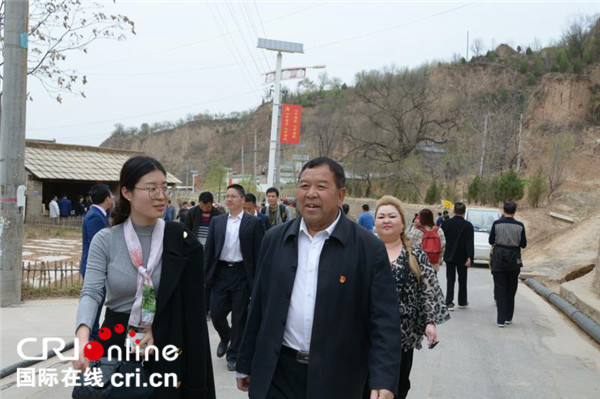 梁家河村现任党总支书记石春阳带领中外游客参观梁家河村.