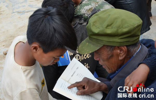 图片默认标题_fororder_彝族老人和孩子翻阅《禁毒宣传读本》-摄影-毛琴