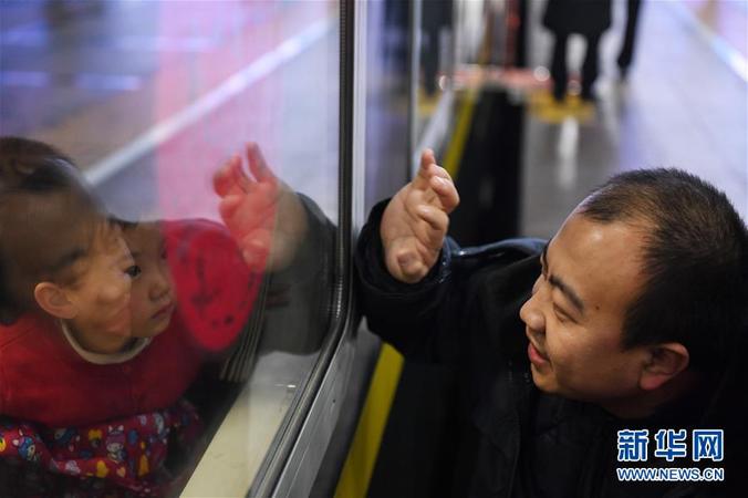 1月10日，在北京火車站K4051次列車前，送別家人的王長付（右）向車內(nèi)的3歲女兒招手。 當(dāng)日，2020年春運(yùn)正式啟動(dòng)。 新華社記者 鞠煥宗 攝