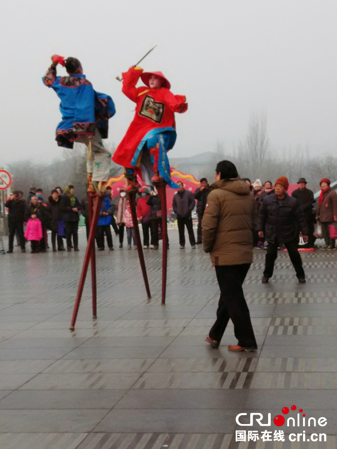离芙蓉街不远的小广场上,民俗表演踩高跷吸引了众多拜年路上的人们