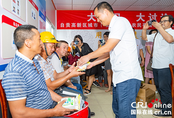 自贡市委组织部副部长赖远驰(右二)向农民工发放防