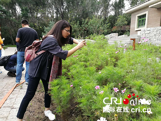 埃及《CHINA TODAY》供稿人梅•阿舒尔被园区内的鲜花吸引，用手机拍照。_fororder_埃及《CHINA TODAY》供稿人梅•阿舒尔被园区内的鲜花吸引，用手机拍照。