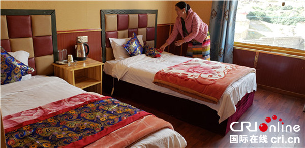 图片默认标题_fororder_洛绒邓珠的妻子正在整理酒店房间。（理塘县委宣传部-供图）