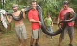 英國《每日郵報》9月18日刊發的照片顯示，圭亞那一名教師發現了一條17英寸的蟒蛇，並將其頭部罩住從河中打撈到岸上，在此之前，這條蟒蛇吞下了一條狗。圖為這名教師和朋友一起與蟒蛇合影