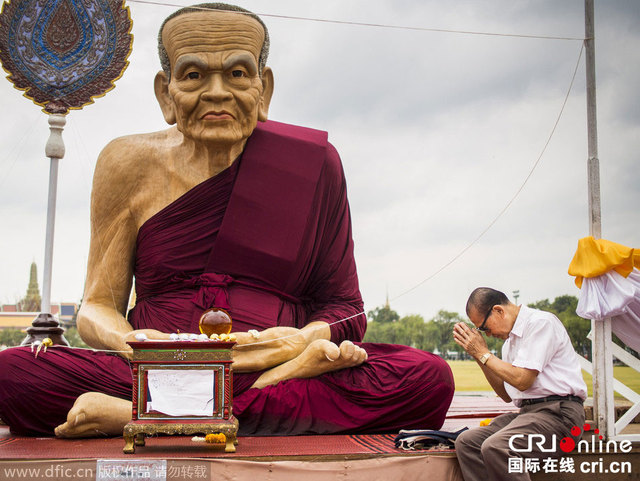 泰国曼谷佛教信徒在名僧巨型雕像前祷告