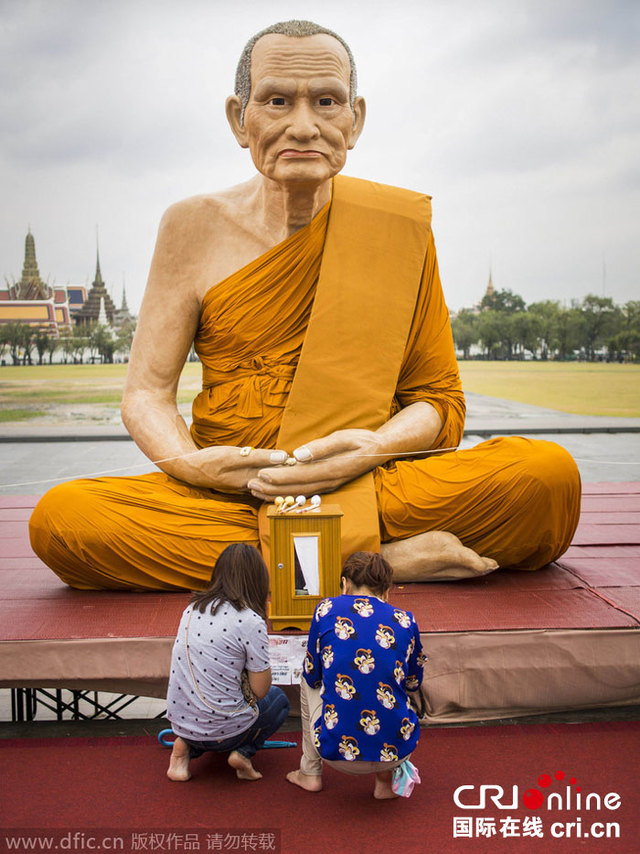 泰国曼谷佛教信徒在名僧巨型雕像前祷告