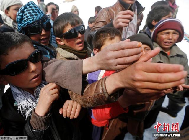 阿富汗雪崩幸存者搬运救援物资 跪雪地祈祷