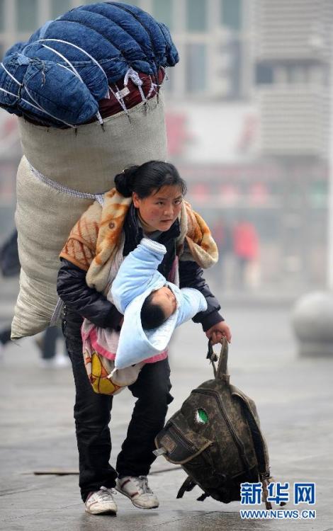 　一位背负着超大行李的母亲怀抱孩子在南昌火车站匆忙赶车（2010年1月30日摄）。 新华社记者 周科 摄 图片来源：新华网