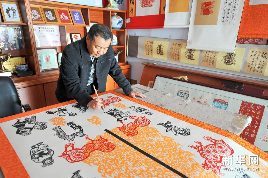 10月29日，河北丰宁满族自治县满族剪纸传承基地，剪纸艺人在给剪纸着色。