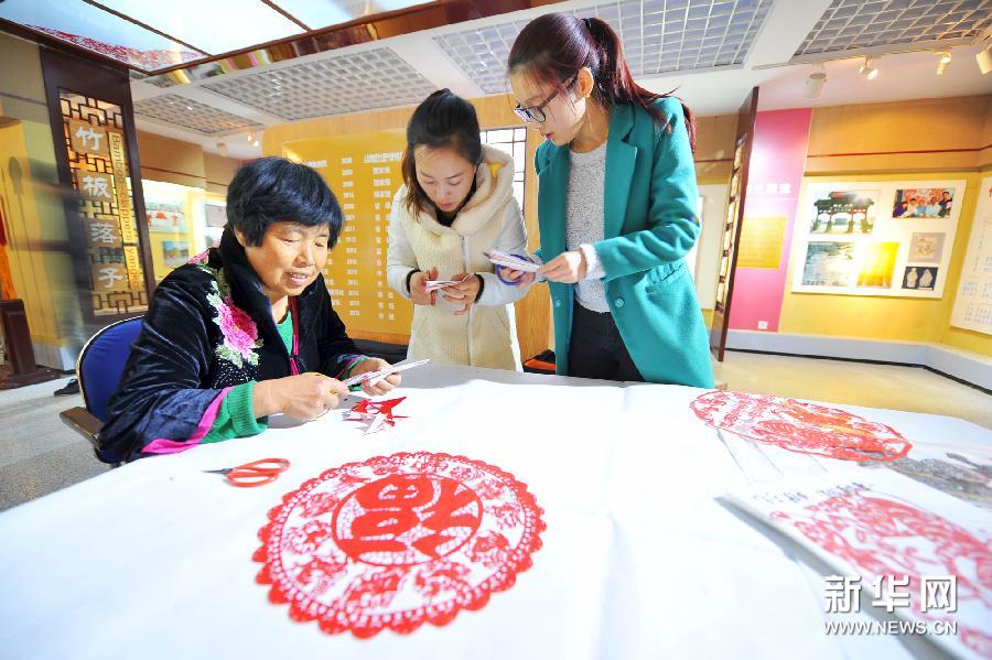 10月29日，在河北丰宁满族自治县非物质文化遗产展馆内，满族剪纸艺人在交流剪纸技艺。