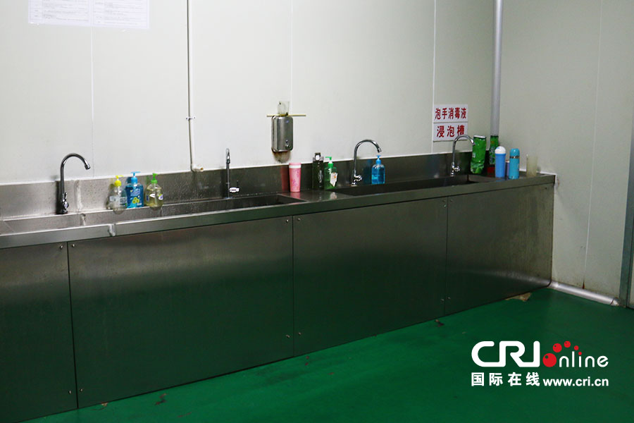工人们在进入包装车间前,先要更换好工作服并佩戴好专用工作帽子,并在这个消毒间清洗双手并消毒。(摄影 刘澄圆)
