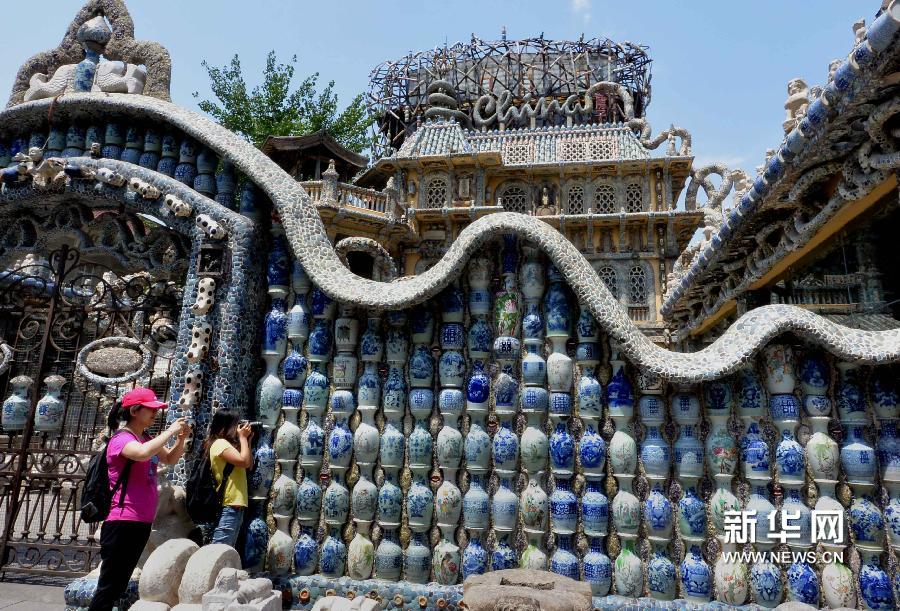 5月17日,两位游客在瓷房子外的“平(瓶)安墙”前拍照。新华网图片 王颂 摄