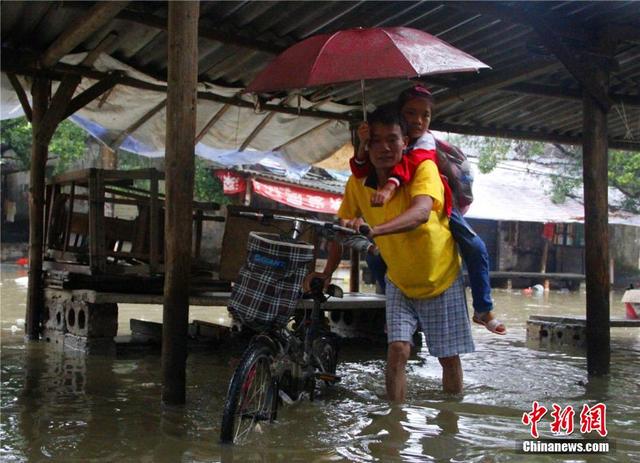 廣西暴雨致街道積水過膝 民眾涉水送子上學