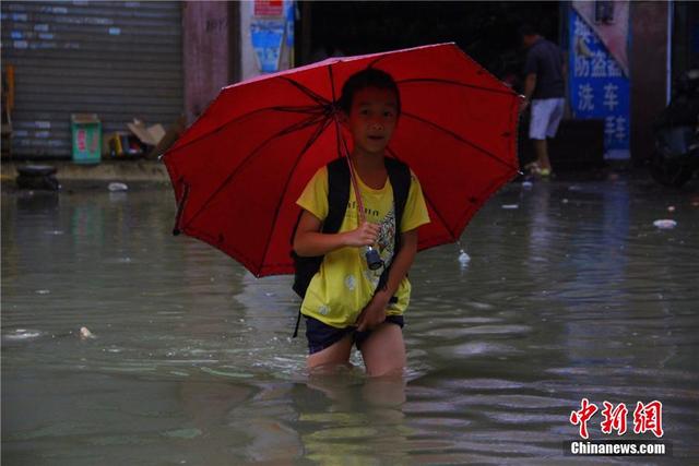 广西暴雨致街道积水过膝 民众涉水送子上学