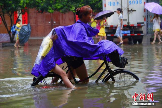 广西暴雨致街道积水过膝 民众涉水送子上学