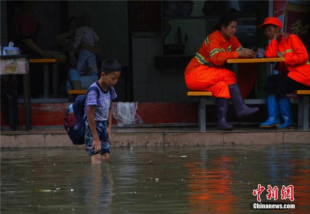 廣西暴雨致街道積水過膝 民眾涉水送子上學