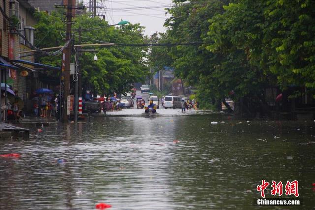 广西暴雨致街道积水过膝 民众涉水送子上学