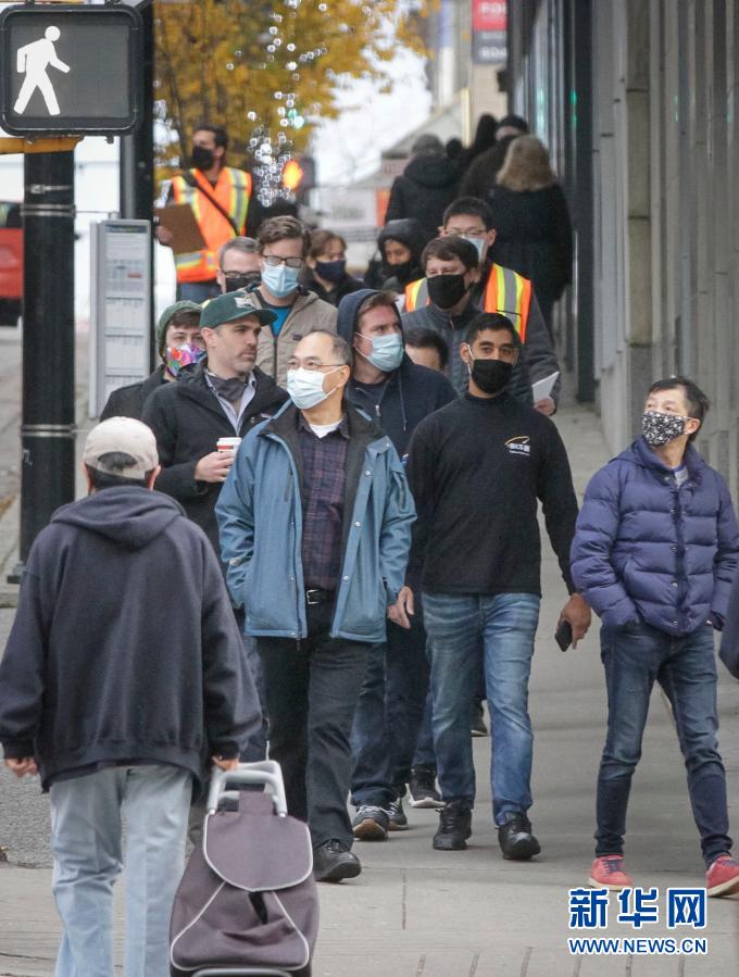 新华社发(梁森摄)   12月3日,在加拿大温哥华,人们戴着口罩出行