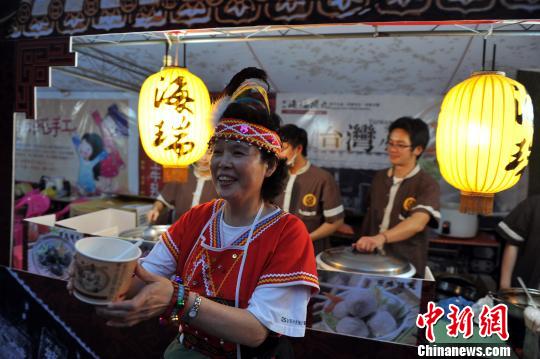 10月26日晚，一位身穿台湾阿美族服饰的阿嬷在向民众推介美味的台湾小吃