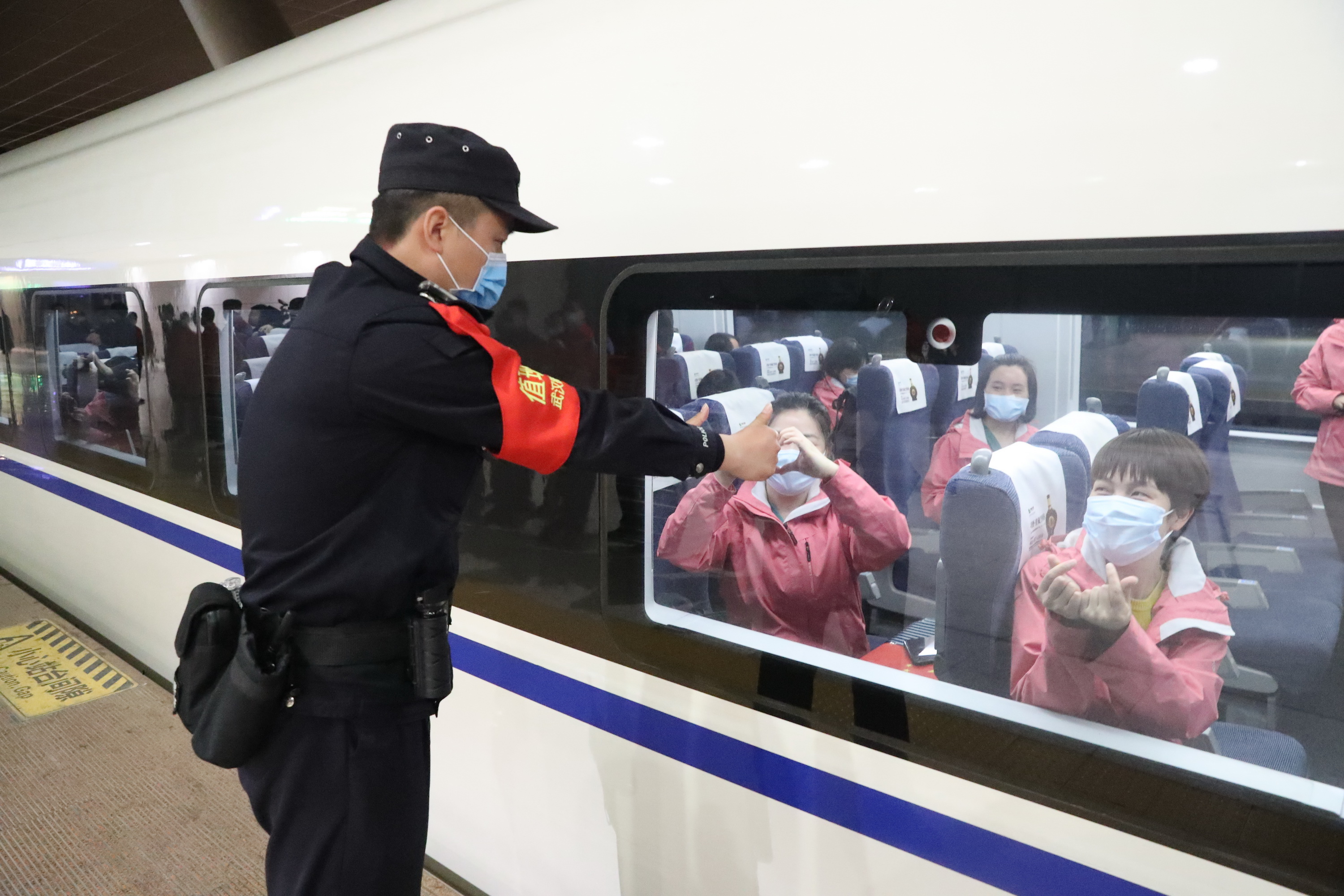 站台上,武汉铁路民警和工作人员向即将归家的英雄们致敬,护航列车