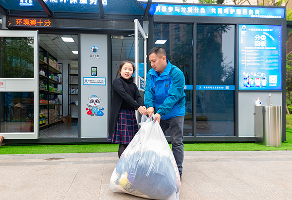 倡导垃圾分类新概念 自贡市首个智能环保服务站正式启用_fororder_4杨紫晨（左）兑换废旧衣服（摄影-廖志全）