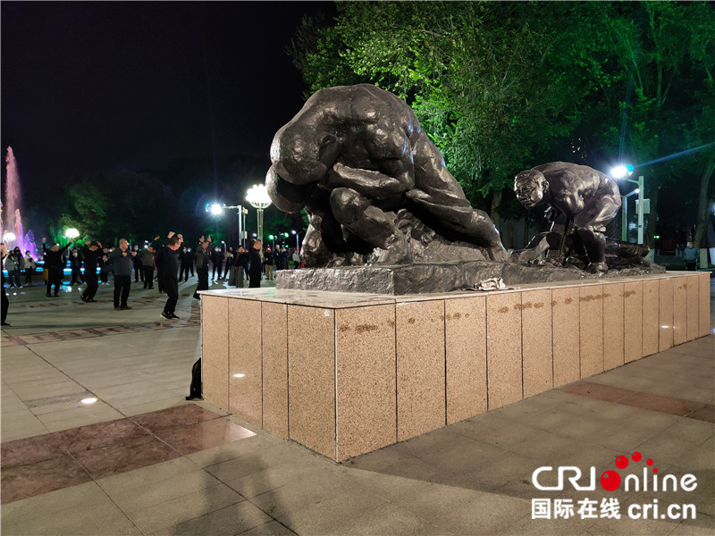 【续写丝路新篇章】新疆兵团军垦博物馆：不忘来时路 不罔肩头担（组图）_fororder_09新疆兵团军垦博物馆对面的雕像——军垦第一犁。夜幕降临，群众在“军垦第一犁”周围跳起欢乐的广场舞。 摄影：位树理