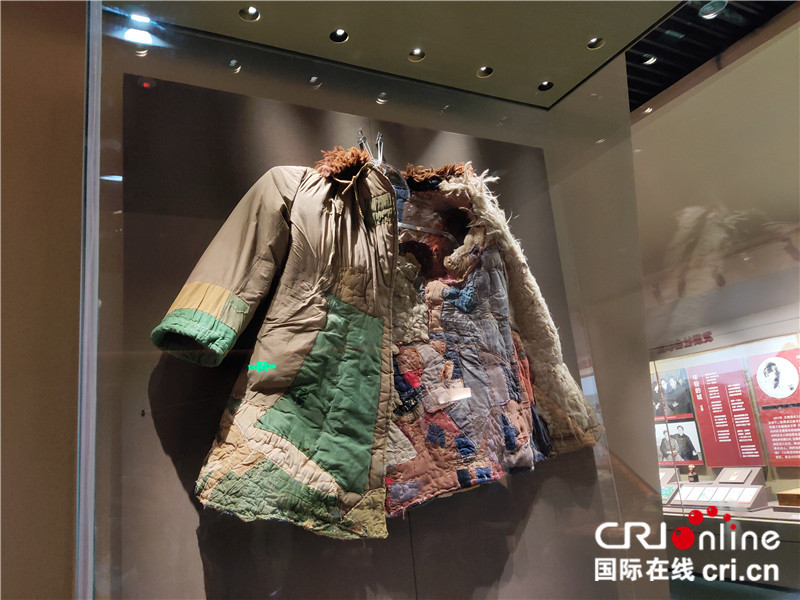 【续写丝路新篇章】新疆兵团军垦博物馆：不忘来时路 不罔肩头担（组图）_fororder_05有着296块补丁的军大衣。为了迅速改变新疆工业落后面貌，驻疆人民解放军把国家支付给他们的军费作为建设资金，广大指战员把自己的津贴投入合作社，并节约菜金、粮食和衣帽鞋袜，连衬衣衣领和口袋都节省下来，累计每人每年节约90余元投入新疆的现代工业建设。 摄影：位树理