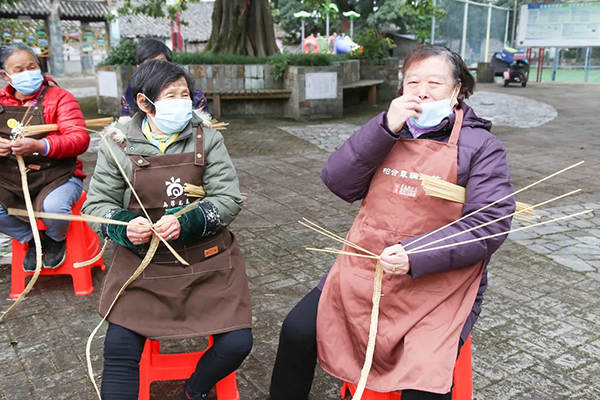 成都市龙泉驿区示范创建“竞进拉练”活动走进柏合街道_fororder_梨花街社区居民正在编柏合草编-供图--成都市龙泉驿区柏合街道办