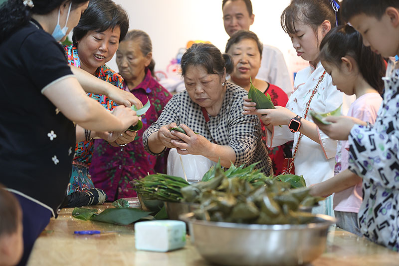 宜宾：儿童节遇上端午 少年儿童感受传统节日习俗_fororder_居民围在一起包粽子