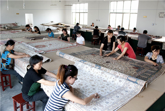 河南南阳：“南召织造”享誉国内外_fororder_南召茧丝毯加工企业地毯修剪车间工人们正在修剪编织好的地毯。