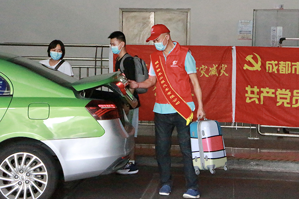 直面高温“烤”验 坚守交通一线——致敬高温下的文明交通守护者_fororder_成都东站出租车司机帮助乘客提放行李-供图-成都市交通运输局
