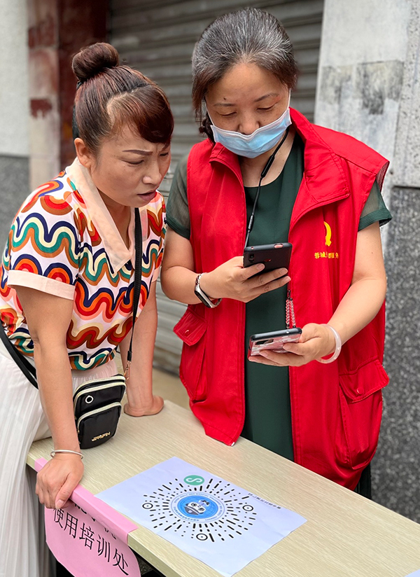 成都温江区柳城街道激活志愿服务“小细胞” 释放社区治理“大能量”_fororder_党员志愿者帮助老人注册蓉城反诈APP-供图-成都市温江区柳城街道