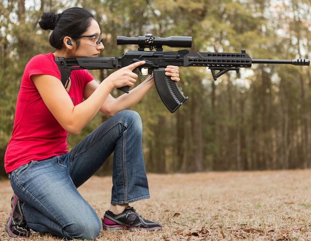 美女手持霰弹枪打靶,配有三角握把和瞄具.