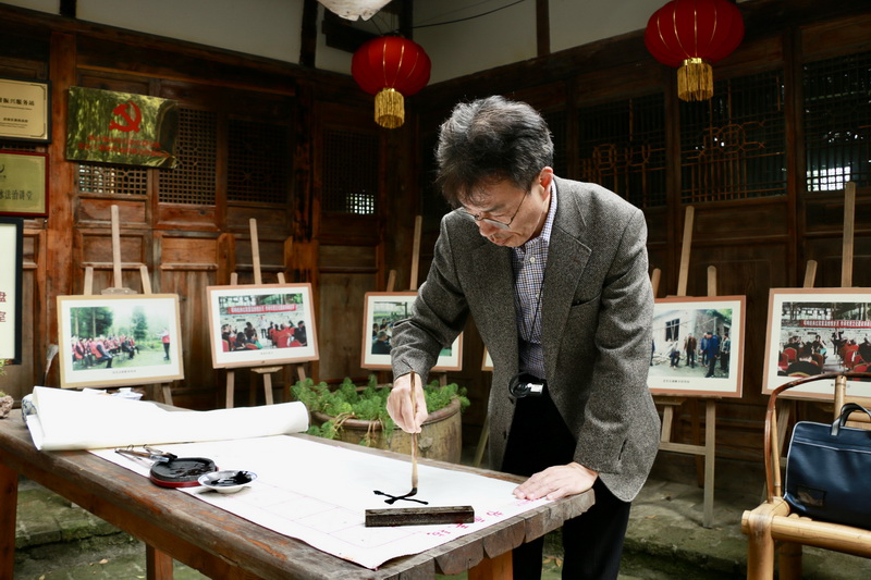 滔滔岷江水 悠悠中华情 外国使领团走进成都都江堰_fororder_日本驻重庆副总领事大熊雅昭写毛笔字 摄影 杨雯涵