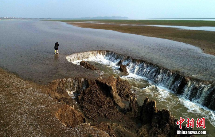 連日來，江西省鄱陽湖地區(qū)出現(xiàn)降雨，湖水不斷增加，該濕地水流量不斷加大，將濕地沖刷成一條小河溝，形成“瀑布”景觀。楊帆 攝