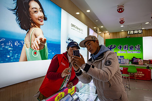 （张）中国电信理塘分公司：让5G网络覆盖“天空之城” 书写网络强国的民族篇章_fororder_中国电信理塘分公司工作人员为当地群众介绍智能手机业务-摄影李永杰