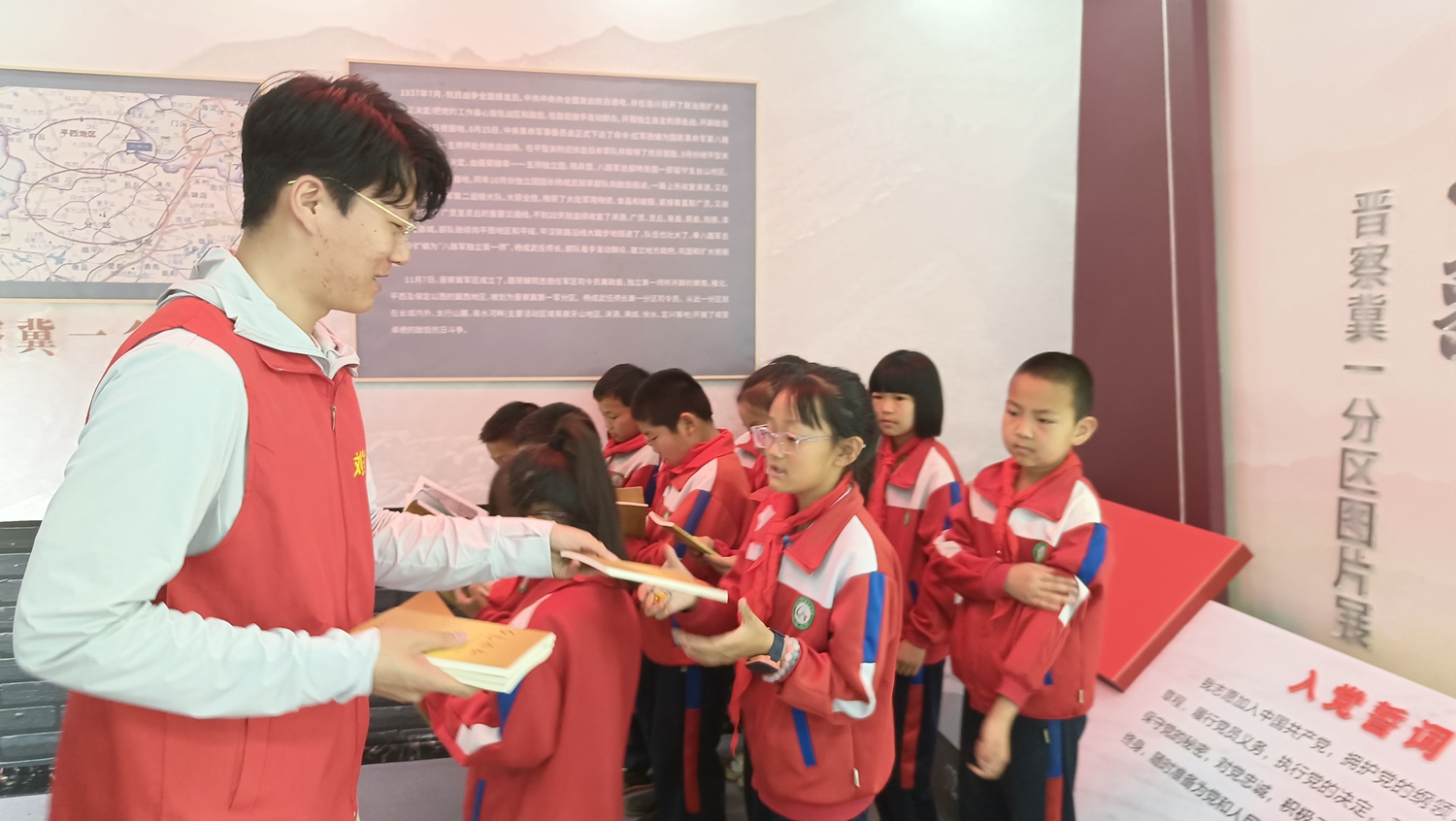 （原创）保定市满城区：山里孩子收到“红色’礼物_fororder_讲解员为学生发放《红色热土》书籍 摄影 陈璐
